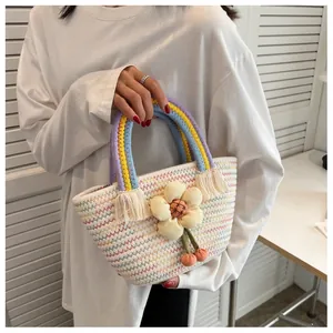 Dettaglio del manico intrecciato arcobaleno e ciondolo a fiore 3D su borsa di paglia