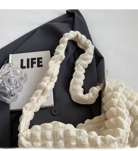 Détail du sac à main crème avec texture gaufrée à bulles et poignée plissée au style moderne
