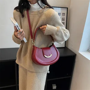 Dettaglio borsa a mezzaluna rosso scuro in pelle con elegante fibbia in metallo dorato