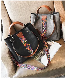 Detail of grey and black tote bags with colorful ethnic woven straps on a soft beige chair