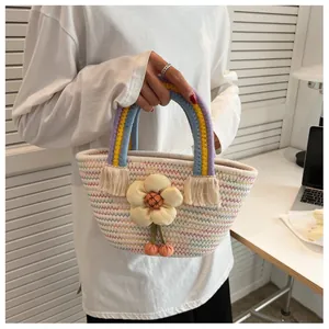 Dettaglio borsa a mano intrecciata con manici arcobaleno e fiore giallo all'uncinetto