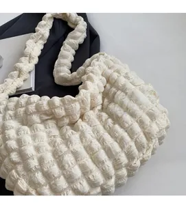 Détail du sac à main blanc matelassé avec bandoulière tressée et texture moelleuse