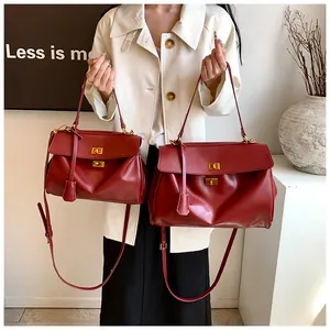 Dettaglio borsa in pelle rossa con chiusura a scatto dorata e tracolla regolabile