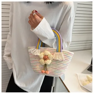 Dettaglio di borsa in paglia intrecciata colorata con ciondolo a fiore 3D e manico