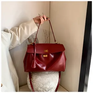 Dettaglio della borsa tote bordeaux in pelle con chiusura girevole dorata e tracolla