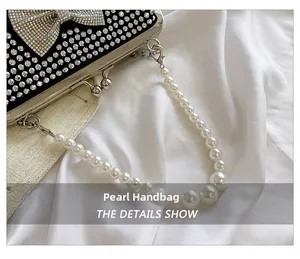 Detail show of pearl handle and rhinestone bow on black evening clutch bag