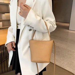 Chic apricot lychee pattern leather bucket bag shown as a stylish crossbody on a model