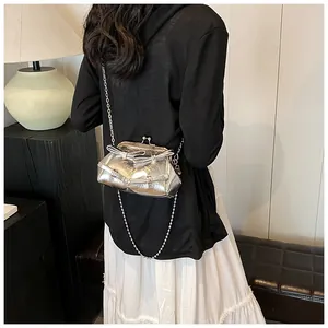 Mini borsa argento a scatto con fiocco metallico e tracolla a catena indossata da modella
