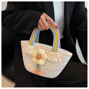 Dettaglio borsa in paglia intrecciata a mano con fiore giallo e manico arcobaleno