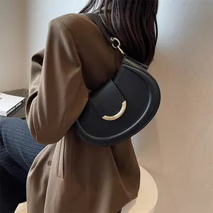 Dettaglio di una borsa a tracolla a mezzaluna in pelle nera con fibbia dorata sul modello