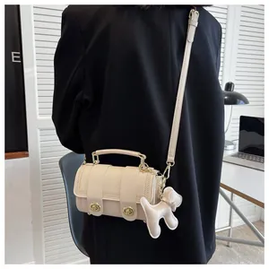 Dettaglio borsa a tracolla beige con cuciture a onde e ciondolo a cane indossata da modella