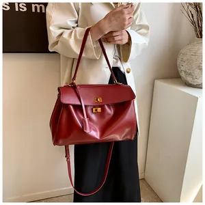 Dettaglio della borsa bordeaux con doppia chiusura in metallo dorato e ampia tracolla in pelle
