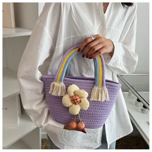 Dettaglio borsa viola tessuta a mano con manico arcobaleno, nappa e fiore in tessuto