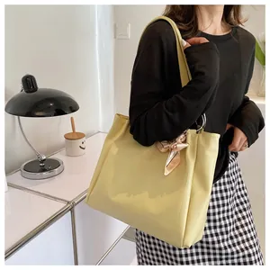 Close-up of yellow large-capacity tote bag with metal rings and decorative scarf detail