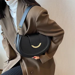 Minimalistische schwarze Satteltasche mit Goldbeschlägen über der Schulter zum Blazer