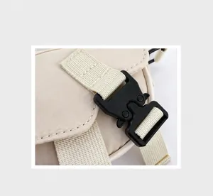 Dettaglio della borsa in nylon beige con fibbia in plastica nera e cinturino rinforzato