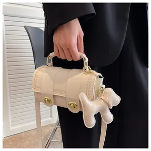Dettaglio borsa cilindrica bianco panna con serrature dorate e ciondolo a forma di cane