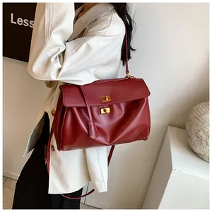 Dettaglio laterale di borsa tote bordeaux in morbida pelle con chiusure dorate eleganti