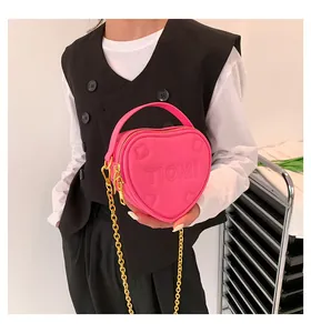 Dettaglio della borsa rosa a forma di cuore con catena dorata e logo in rilievo