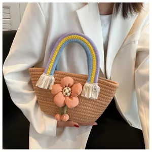 Dettaglio della borsa in paglia intrecciata a mano con manico arcobaleno e decori floreali