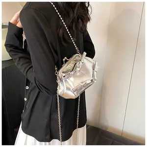 Dettaglio della borsa a spalla argento metallizzato con fiocchi e catena indossata dal modello
