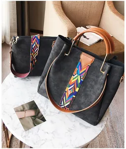 Detail view of black tote and small shoulder bag set with colorful woven strap on marble