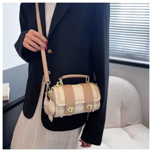 Dettaglio della borsa cilindrica beige con bordo intrecciato e ciondolo a orsetto