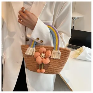 Dettaglio borsa in paglia con grande applicazione floreale e nappe arcobaleno