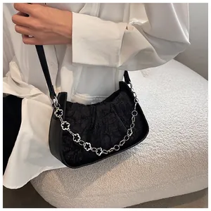 Dettaglio della borsa a spalla nera a pieghe con catena decorativa a fiori in metallo