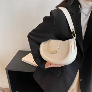 Dettaglio borsa a mezzaluna beige con fibbia dorata e finitura opaca testurizzata