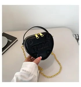 Dettaglio della mini borsa a cuore con logo in rilievo e tracolla a catena oro