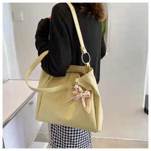 Close-up of a pale yellow tote bag with a floral scarf accent and silver metal ring detail