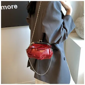 Dettaglio mini borsa in pelle verniciata rossa con fiocco e tracolla a catena d'oro