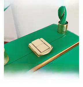 Detail of green acrylic box bag showing golden metal clasp and woven handle craftsmanship
