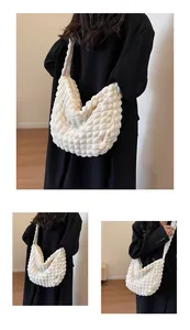 Détail du sac à bandoulière blanc à texture bulles porté par un mannequin en ville