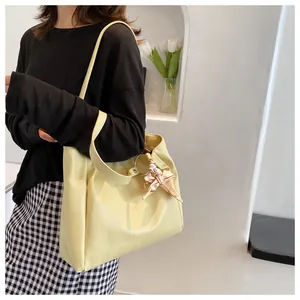 Close-up of cream tote bag with crocodile texture and pink satin bow charm