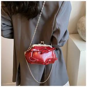 Dettaglio mini borsa rossa con chiusura a scatto, fiocchi e catena in argento