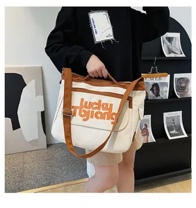 Dettaglio della borsa in tela con finiture marroni e scritta Lucky Tbjiang sul davanti