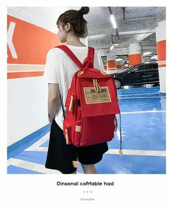 Scatto esterno dello zaino casual rosso brillante in tessuto resistente e patch retro