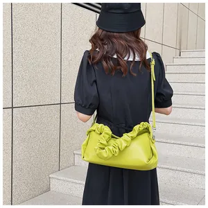 Dettaglio borsa a tracolla verde neon con manico a nuvola increspato su modella in abito nero