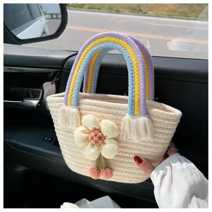 Dettaglio borsa in paglia intrecciata con manici arcobaleno e grande fiore in 3D