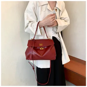 Dettaglio borsa tote in pelle bordeaux con doppia chiusura dorata e tracolla regolabile