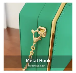 Close-up of golden metal hooks and chain links on a green acrylic box clutch bag