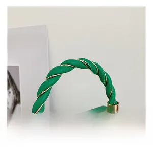Detail of green acrylic box bag showing the woven handle with gold wire and metal hardware