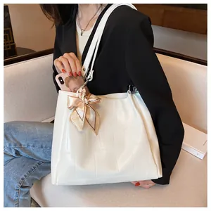 Detailed close-up of white crocodile pattern tote bag featuring an elegant silk bow accent