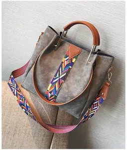 Macro detail of grey faux suede bucket bag with colorful woven strap and brown handles