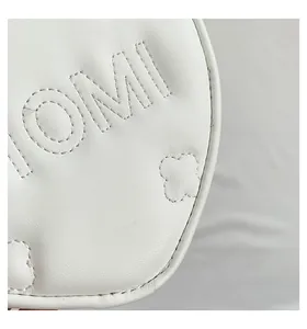 Vista macro di borsa in pelle bianca con logo OMI a rilievo e motivo a quadrifoglio