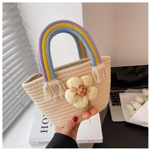 Dettaglio borsa di paglia con fiore in tessuto giallo e manico intrecciato arcobaleno