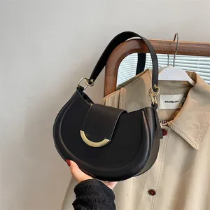 Borsa a spalla semiluna nera con fibbia dorata mostrata in un contesto di vita reale