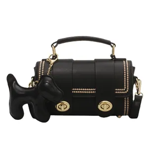 Elegante borsa nera a tracolla con borchie dorate e ciondolo a forma di cane su sfondo bianco